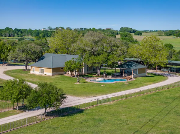 a view of a big house with a big yard and large trees