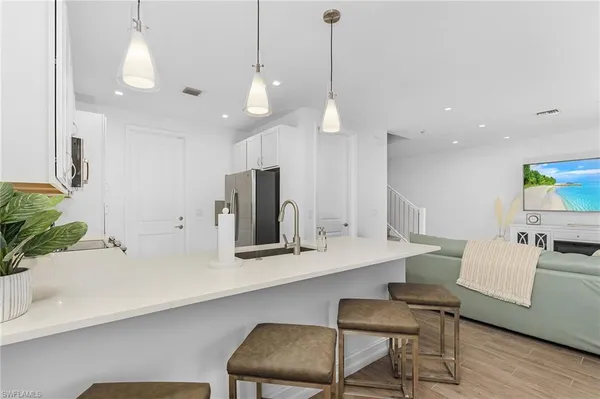 a kitchen with stainless steel appliances a table chairs refrigerator and microwave