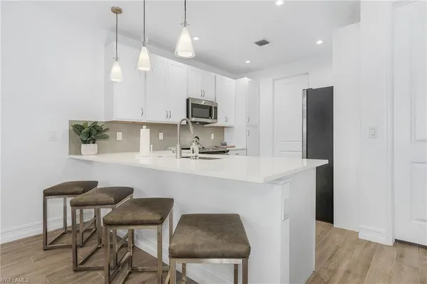 a kitchen with kitchen island white cabinets and stainless steel appliances