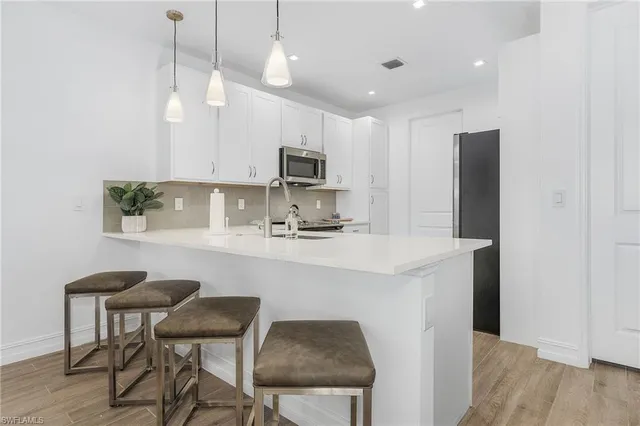 a kitchen with kitchen island white cabinets and stainless steel appliances