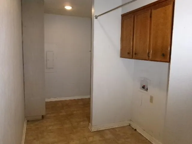 an empty room with wooden floor chandelier fan and windows