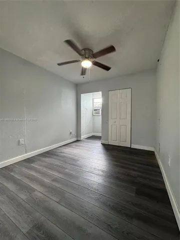 a view of an empty room with wooden floor and a ceiling fan