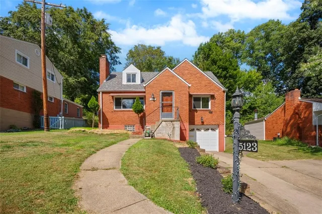 a front view of a house with a garden and trees
