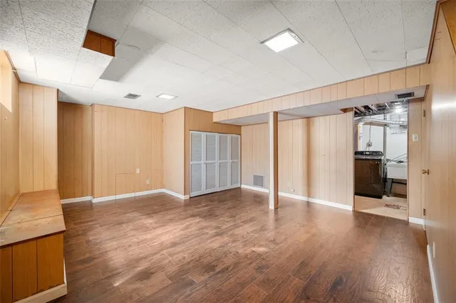 a view of an empty room with wooden floor and a kitchen