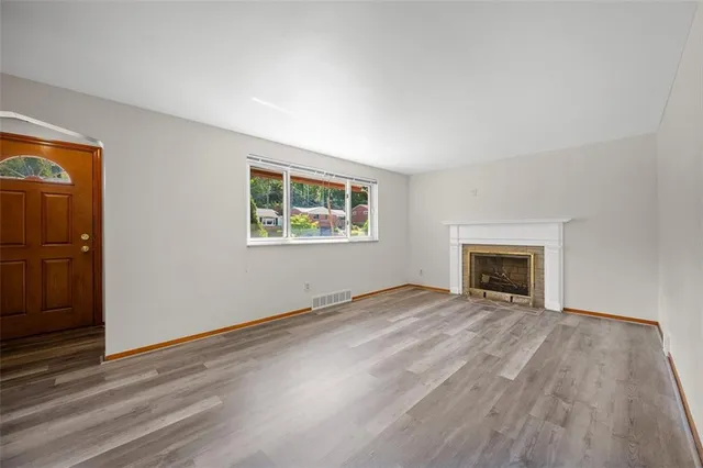 an empty room with windows and fireplace