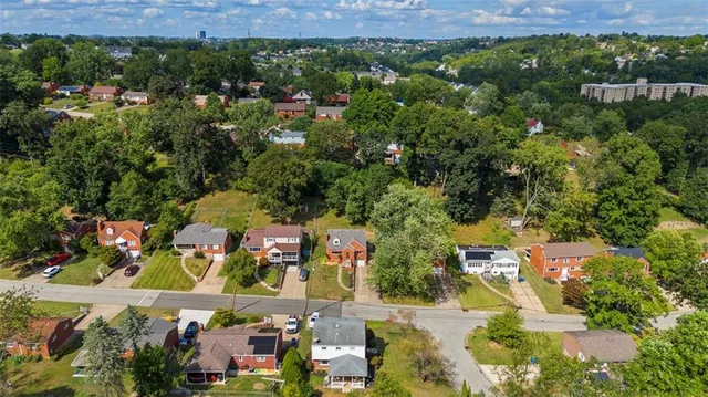 an aerial view of residential houses with outdoor space and trees
