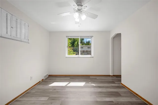 an empty room with a chandelier fan and windows