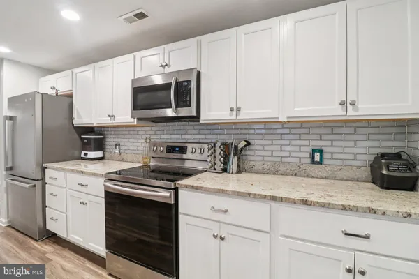 a kitchen with granite countertop white cabinets white stainless steel appliances and sink