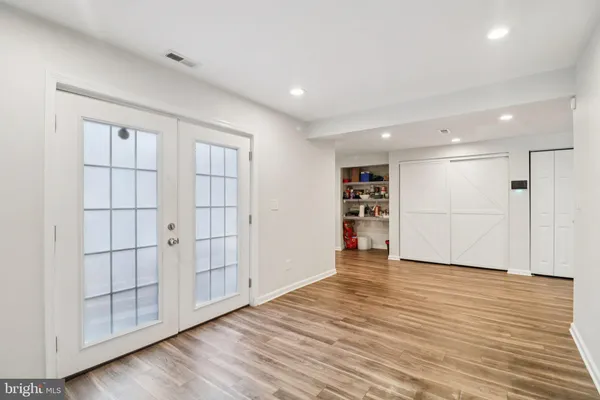 a view of an empty room with wooden floor and closet