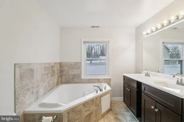 a bathroom with a tub sink and mirror