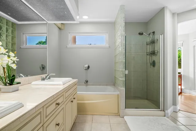 a bathroom with a tub sink shower and two mirror