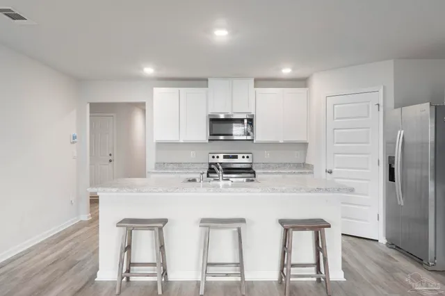 a kitchen with stainless steel appliances granite countertop a white cabinets and a refrigerator
