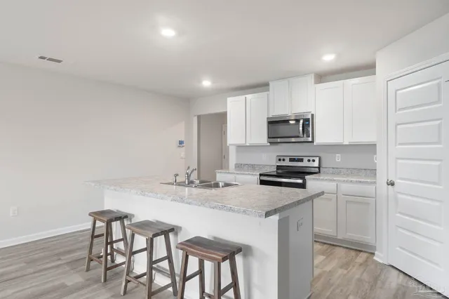 a kitchen with kitchen island granite countertop a stove cabinets and wooden floor