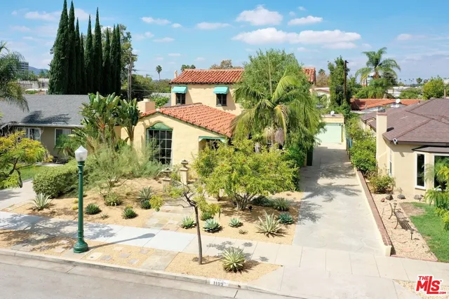 a view of a white house with flower plants