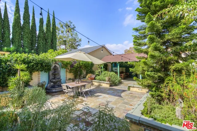 a view of a patio with table and chairs potted plants and floor to ceiling window