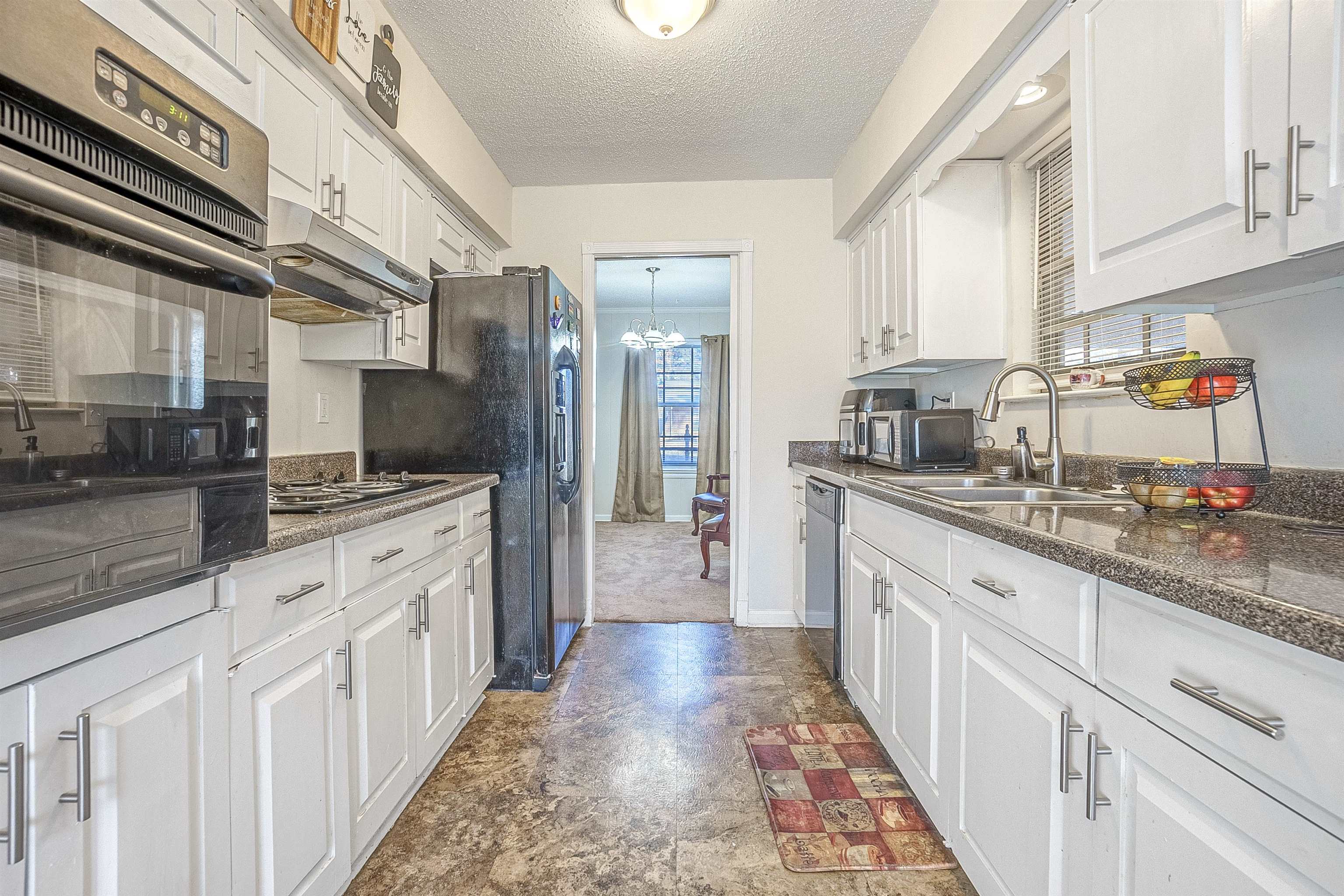 3467 Fox Meadows Road Memphis, TN 38115 - Photo 6 of 15 Kitchen featuring sink, an inviting chandelier, stainless steel appliances, a textured ceiling, and white cabinets