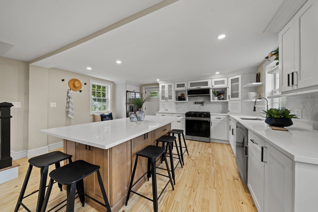 162 High Street, Unit B Danvers, MA 01923 - Photo 7 of 32 a kitchen with stainless steel appliances kitchen island a table and chairs in it