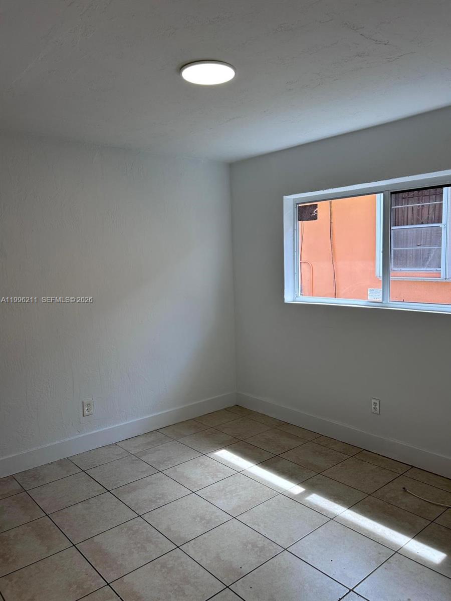 1128 Northwest 76th Street Miami, FL 33150 - Photo 10 of 25 an empty room with a empty space and a window
