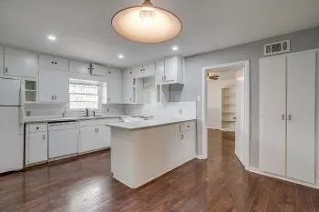 a large kitchen with cabinets wooden floor and a sink