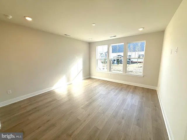 a view of a big room with wooden floor and windows