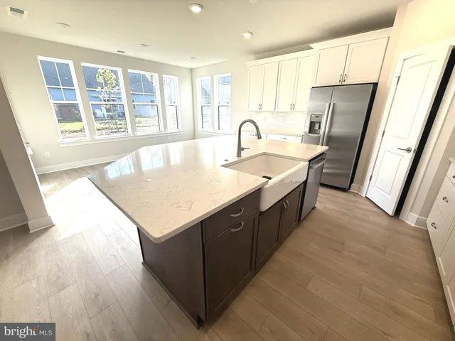 a kitchen with stainless steel appliances granite countertop a sink a refrigerator and wooden floors