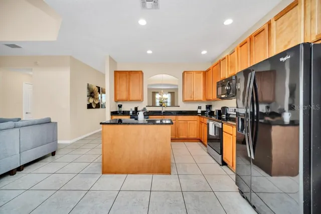 a kitchen with stainless steel appliances granite countertop a refrigerator a sink a stove top oven and cabinets