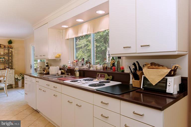 12104 Stirrup Road Reston, VA 20191 - Photo 13 of 27 a kitchen with kitchen island granite countertop white cabinets and white appliances