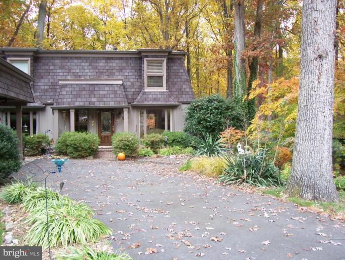 12104 Stirrup Road Reston, VA 20191 - Photo 25 of 27 a view of a brick house with a yard plants and large tree