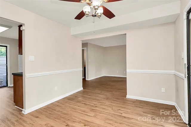 wooden floor in an empty room with a chandelier fan