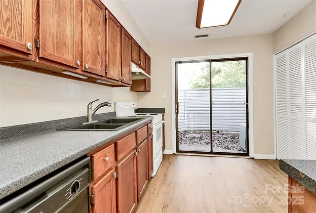 a kitchen with stainless steel appliances granite countertop a sink a stove cabinets and a window
