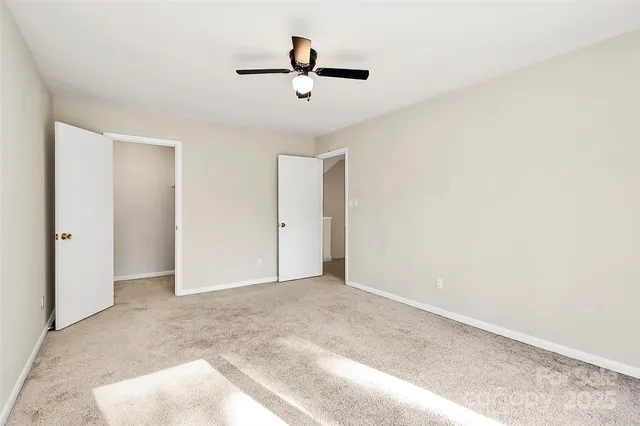 an empty room with a ceiling fan and window