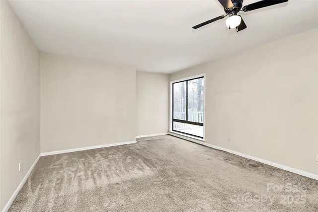 an empty room with a ceiling fan and a window