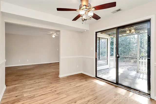 a view of a big room with wooden floor a ceiling fan and front door