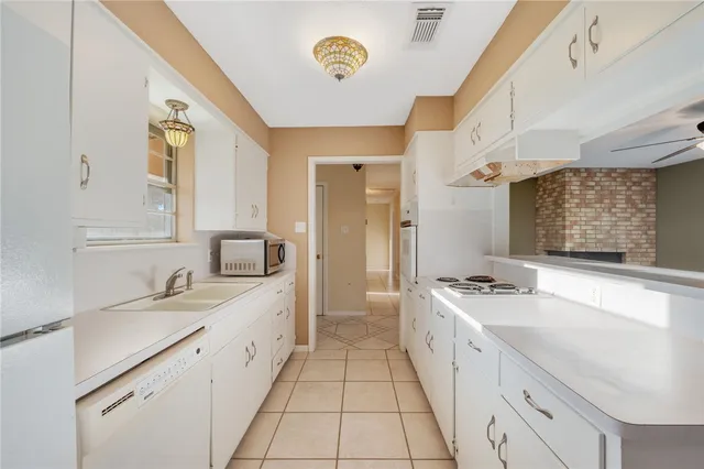 a large white kitchen with a stove a sink a chimney and a refrigerator