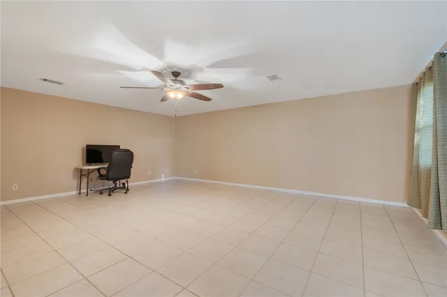 an empty room with windows and ceiling fan