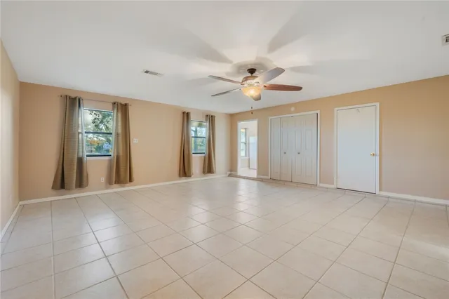 an empty room with windows and fan
