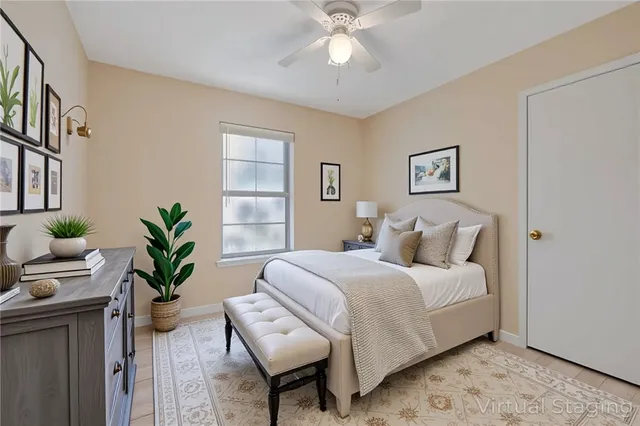 a bedroom with a bed table chair and a potted plant