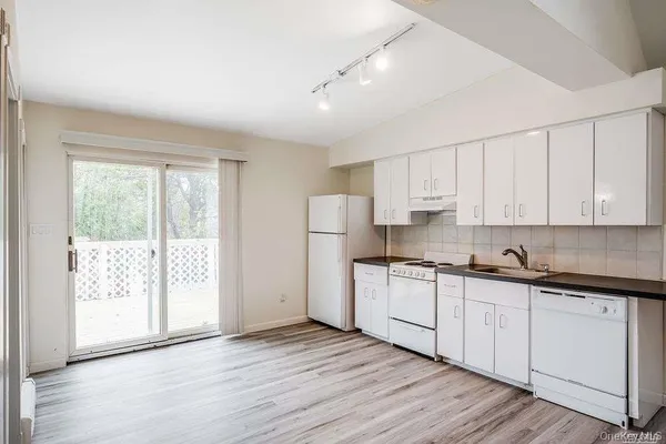 a kitchen with stainless steel appliances granite countertop a stove a sink and white cabinets with wooden floor