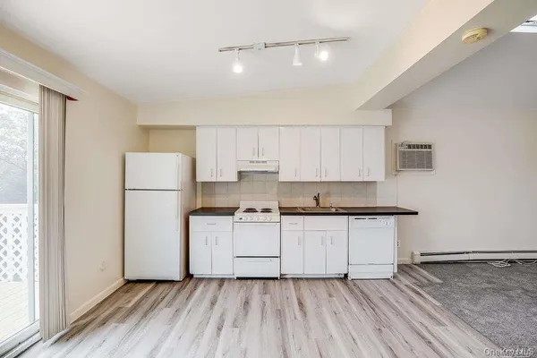 a kitchen with a sink a refrigerator and white cabinets