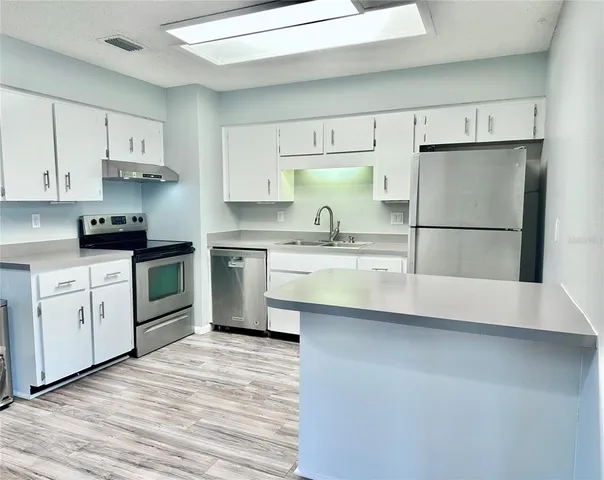 a kitchen with white cabinets stainless steel appliances and sink