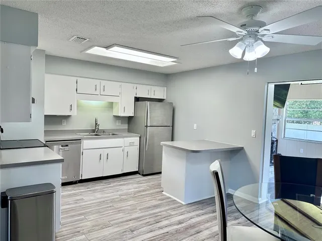 a kitchen that has a lot of cabinets a island and appliances in it