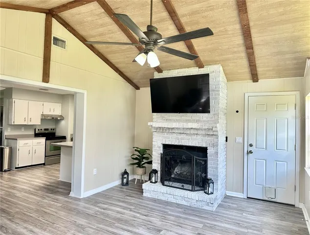 a view of a livingroom with a fireplace a chandelier and wooden floor