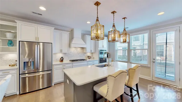 a kitchen with stainless steel appliances a dining table chairs a refrigerator and cabinets