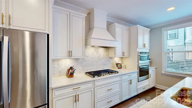 a kitchen with white cabinets and refrigerator