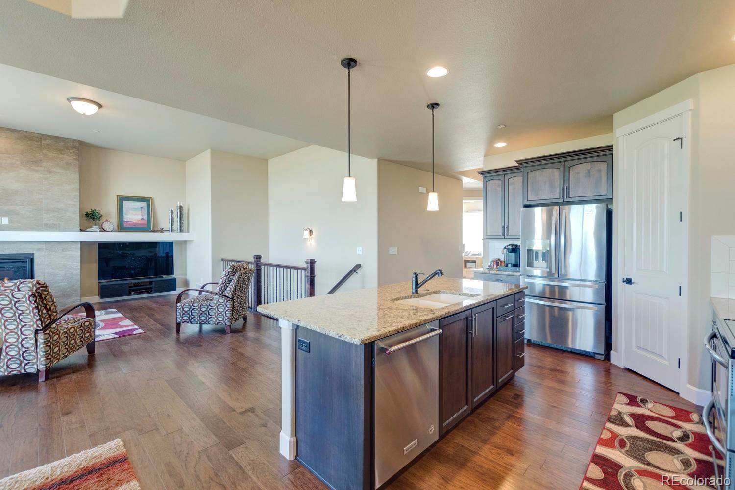 4188 Meadowlark Road Fort Lupton, CO 80621 - Photo 12 of 36 a kitchen with stainless steel appliances granite countertop a sink refrigerator and wooden floor