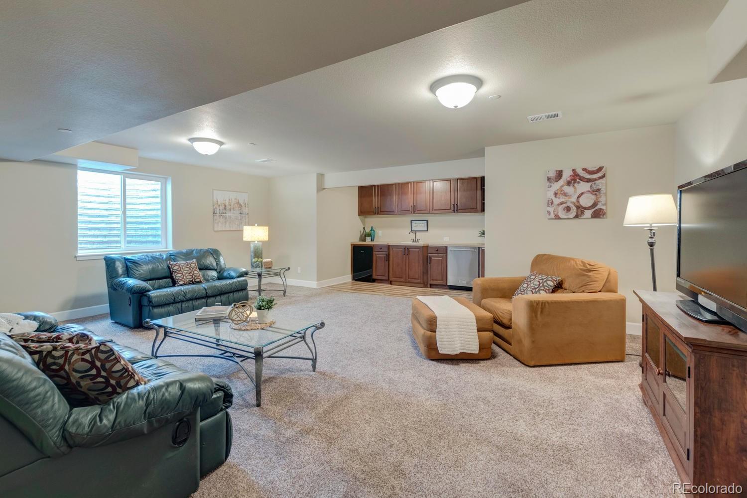 4188 Meadowlark Road Fort Lupton, CO 80621 - Photo 24 of 36 a living room with furniture and a flat screen tv