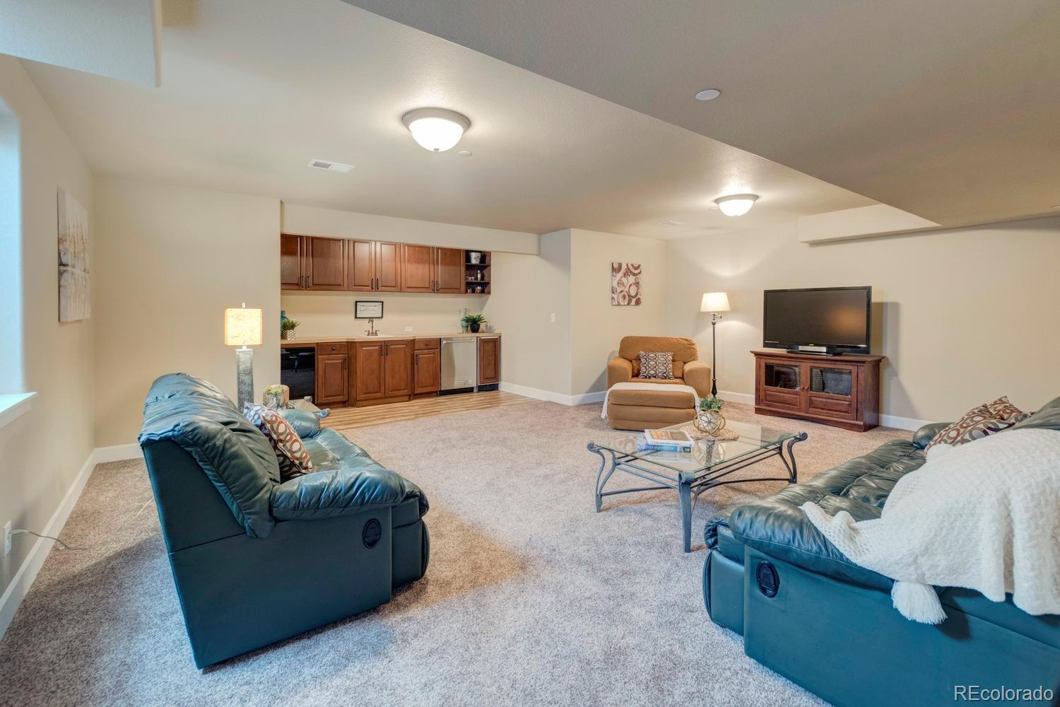 4188 Meadowlark Road Fort Lupton, CO 80621 - Photo 26 of 36 a living room with furniture and a flat screen tv