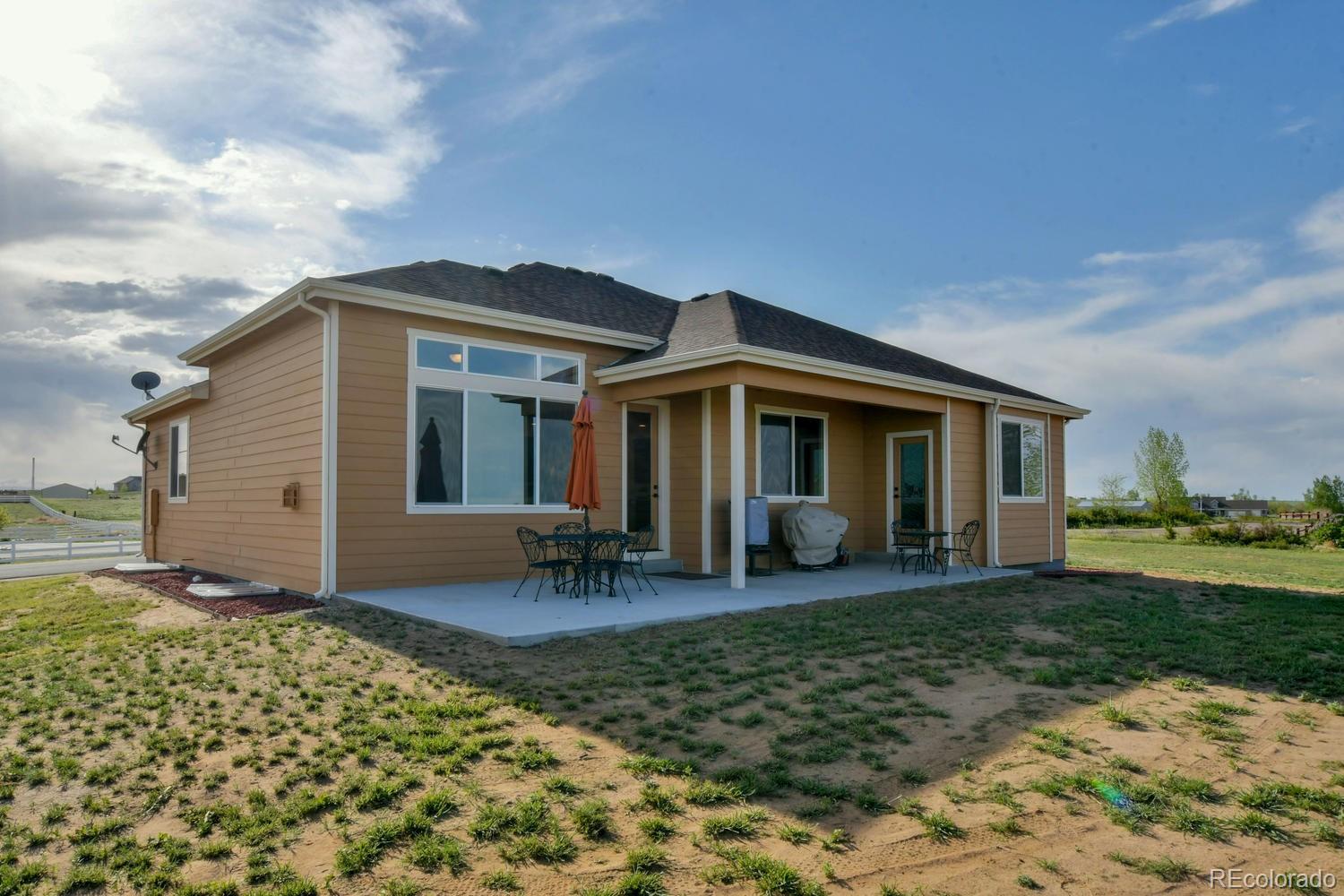 4188 Meadowlark Road Fort Lupton, CO 80621 - Photo 33 of 36 a front view of a house with a garden and porch