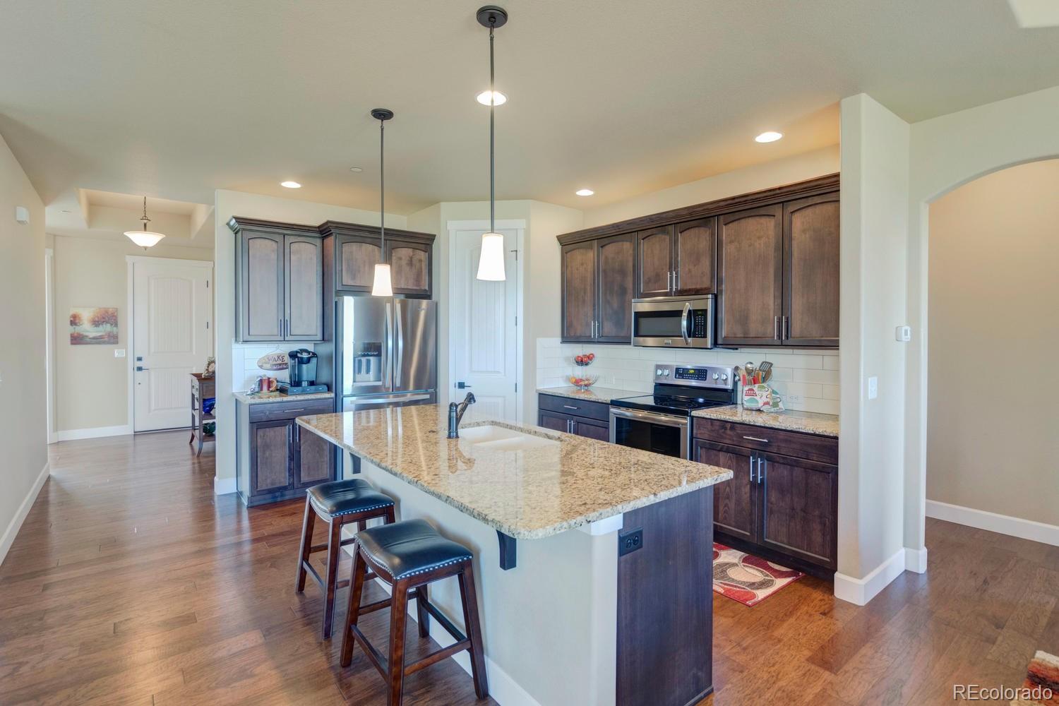 4188 Meadowlark Road Fort Lupton, CO 80621 - Photo 7 of 36 a kitchen with stainless steel appliances granite countertop a refrigerator a stove a sink a dining table and chairs