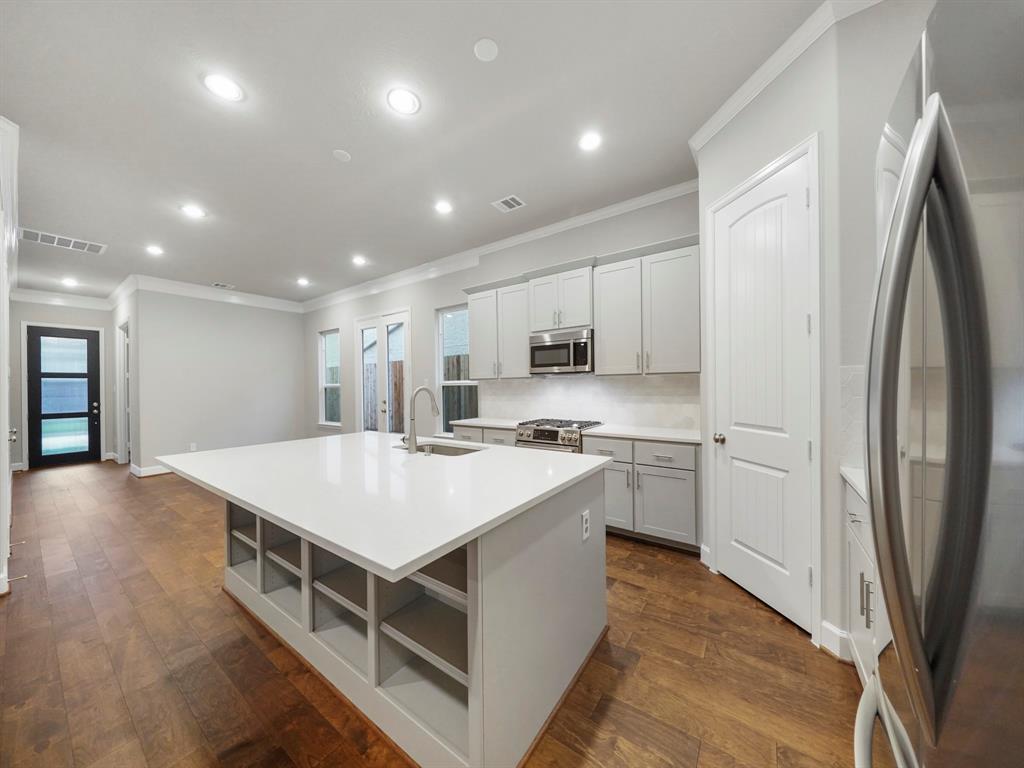 a large kitchen with stainless steel appliances a white stove top oven and white cabinets